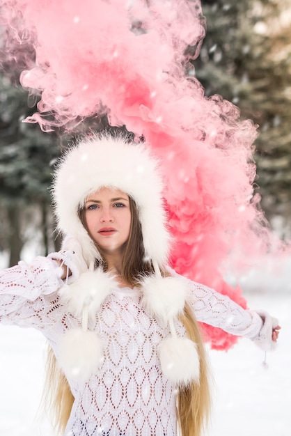 Jeune et jolie femme avec une bombe fumigène rouge dans le parc