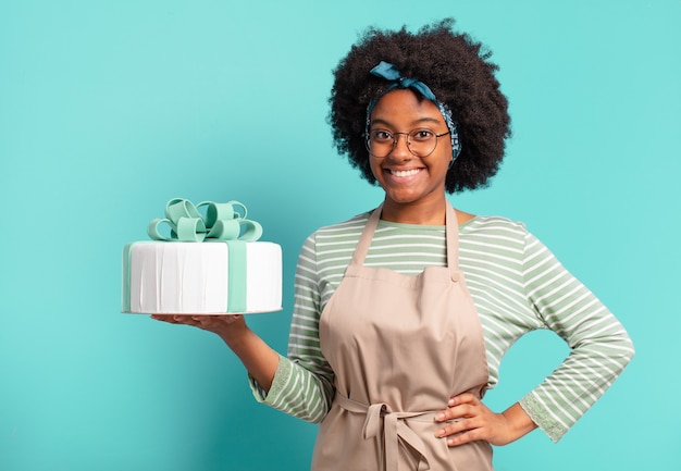 Jeune jolie femme boulangère afro avec un gâteau d'anniversaire