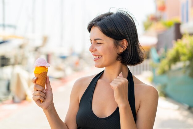 Jeune jolie femme bulgare avec une glace au cornet à l'extérieur célébrant une victoire