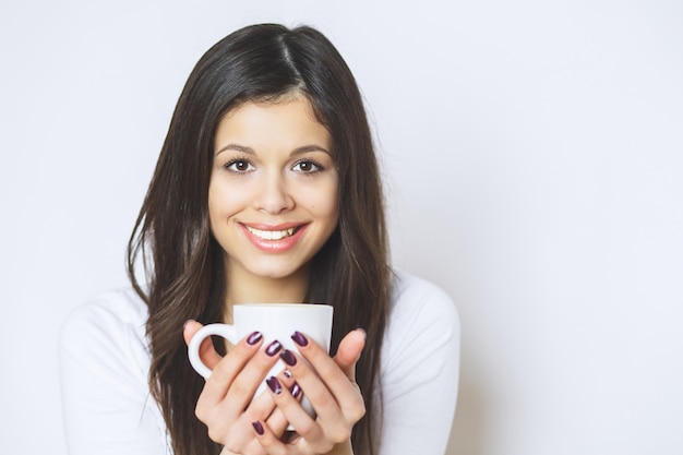 Jeune jolie femme buvant du café ou du thé