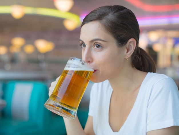 jeune jolie femme buvant une pinte de bière dans un restaurant américain