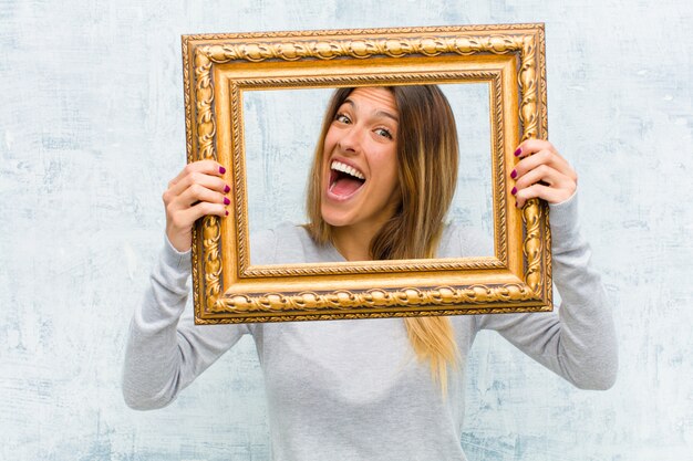 Photo jeune jolie femme avec un cadre baroque sur le mur de grunge