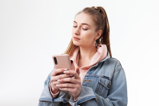 Jeune jolie femme caucasienne à l'aide de smartphone isolé sur fond blanc