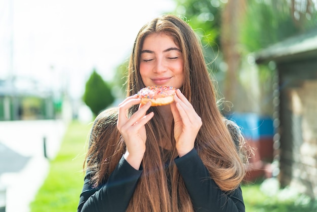 Une jeune et jolie femme caucasienne tenant un donut.