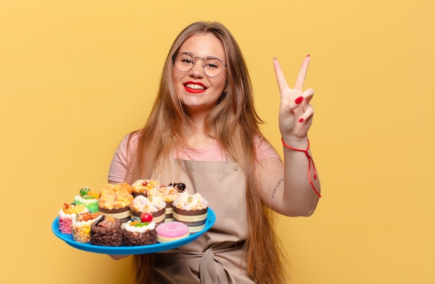 Jeune jolie femme. célébrer un triomphe comme un boulanger gagnant avec des cupcakes