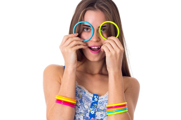 Jeune jolie femme en chemise blanche et bleue faisant des verres de ses bracelets colorés en studio