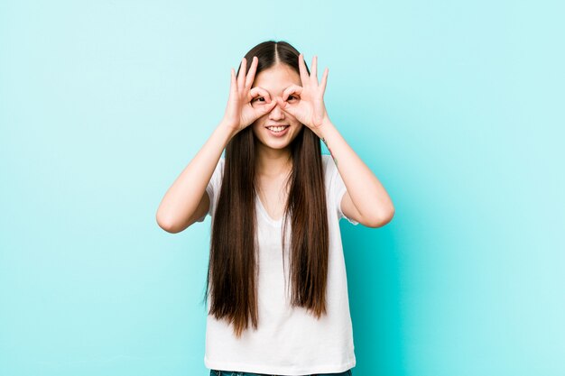 Jeune jolie femme chinoise montrant un signe correct sur les yeux