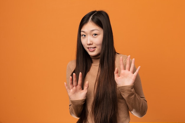 Photo jeune jolie femme chinoise rejetant une personne montrant un geste de dégoût.