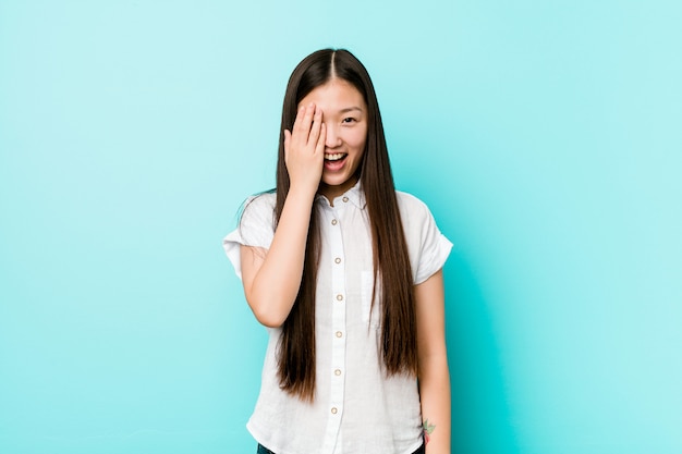 Jeune jolie femme chinoise s'amuser couvrant la moitié du visage avec la paume.