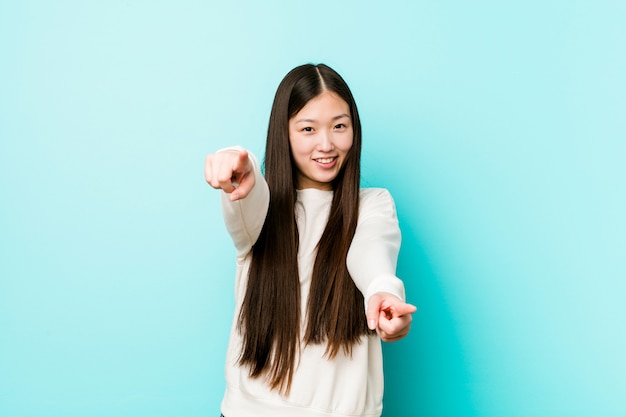 Jeune jolie femme chinoise sourires joyeux pointant vers l'avant.