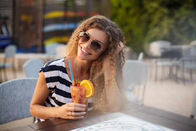 Jeune jolie femme avec cocktail en terrasse de café