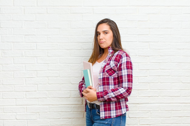 Jeune jolie femme contre la texture du mur de briques