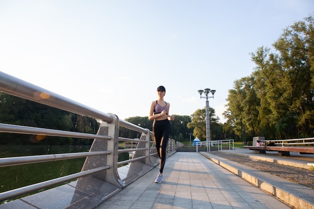 Jeune jolie femme avec un corps mince parfait qui court à l'extérieur. Concept de remise en forme et de course.