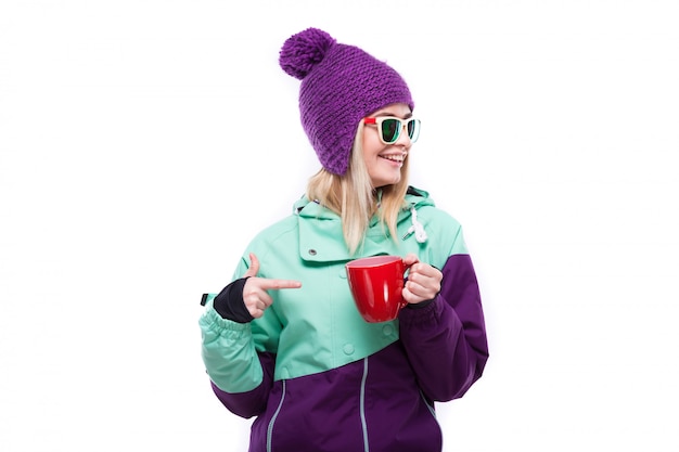 Jeune jolie femme en costume de ski pourpre tenir une tasse rouge