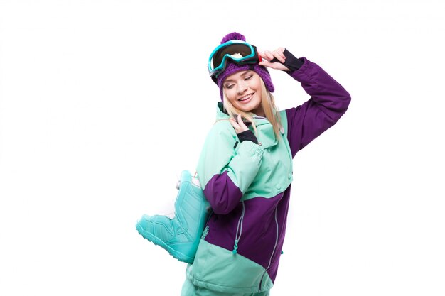 jeune jolie femme en costume de ski violet tenir des bottes de neige