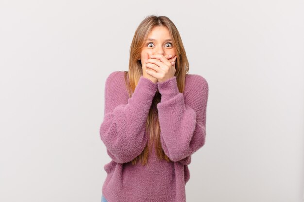 Jeune jolie femme couvrant la bouche avec les mains avec un choc