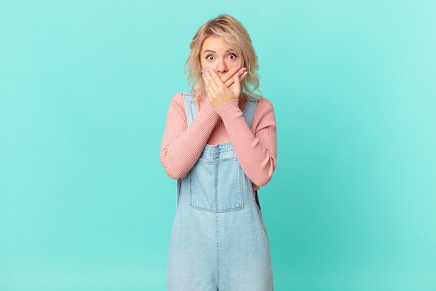 Jeune jolie femme couvrant la bouche avec les mains avec un choc