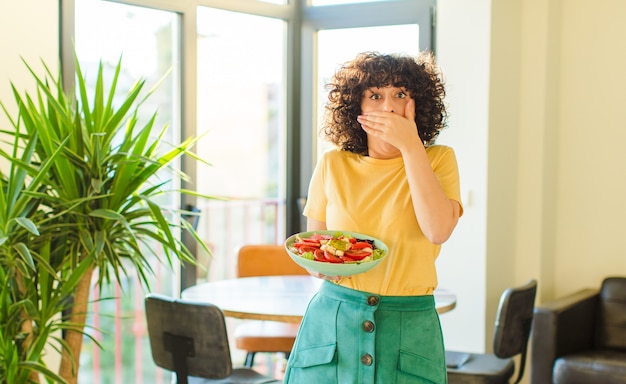 Jeune jolie femme couvrant la bouche avec les mains avec un choqué