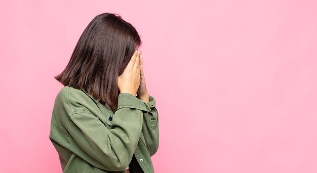 Jeune jolie femme couvrant les yeux avec les mains avec un regard triste et frustré de désespoir, de pleurs, de vue latérale