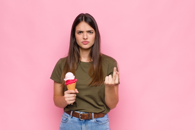 Jeune jolie femme avec une crème glacée se sentir en colère, ennuyé, rebelle et agressif, retournant le majeur, ripostant