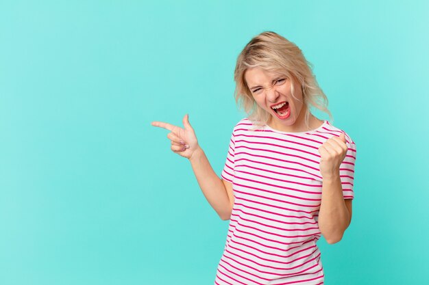 Jeune jolie femme criant agressivement avec une expression fâchée