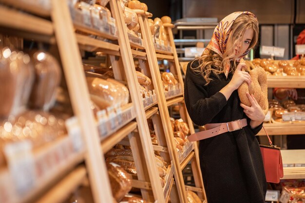 La jeune jolie femme dans le rayon pain du supermarché