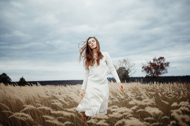 Jeune jolie femme debout dans le champ avec du blé