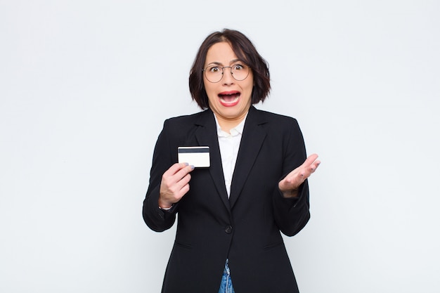 Jeune jolie femme désespérée et frustrée, stressée, malheureuse et ennuyée, criant et criant avec une carte de crédit