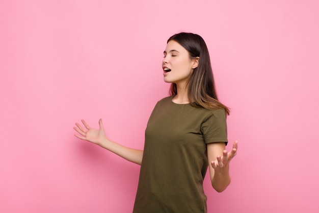 Photo jeune jolie femme effectuant l'opéra ou chantant lors d'un concert ou d'un spectacle, se sentir romantique, artistique et passionné contre le mur rose