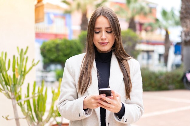 Jeune jolie femme à l'extérieur à l'aide d'un téléphone portable