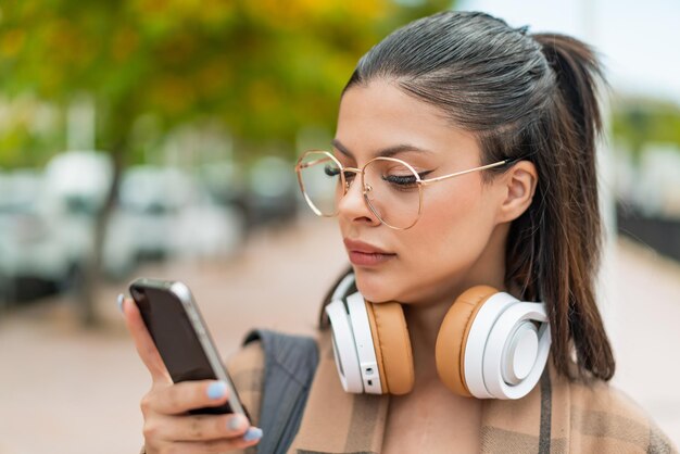 Photo jeune jolie femme à l'extérieur à l'aide d'un téléphone portable