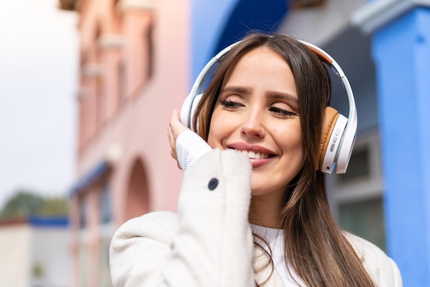 Jeune jolie femme à l'extérieur, écouter de la musique