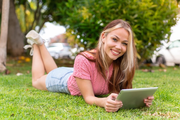 Jeune jolie femme à l'extérieur tenant une tablette