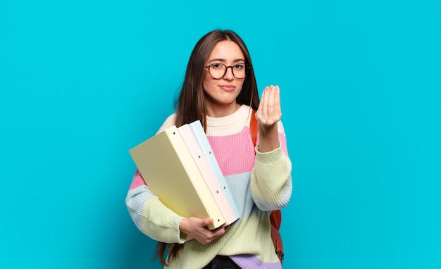 Jeune jolie femme faisant un capice ou un geste d'argent, vous disant de payer vos dettes !