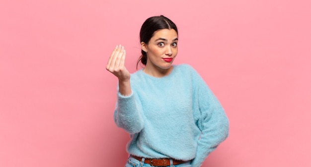 Jeune jolie femme faisant un capice ou un geste d'argent, vous disant de payer vos dettes !