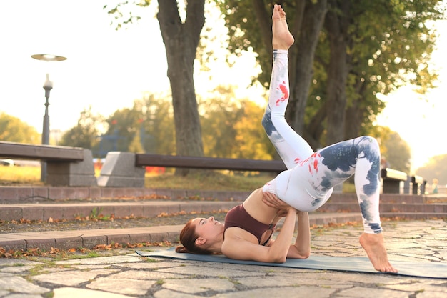 Jeune jolie femme faisant des exercices de yoga dans le parc.