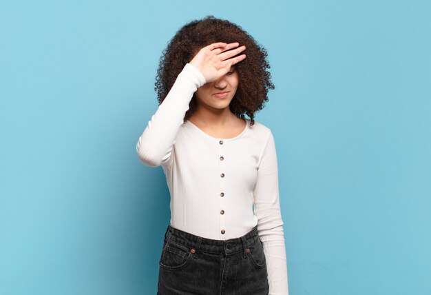 Jeune jolie femme faisant des gestes sur un mur de couleur