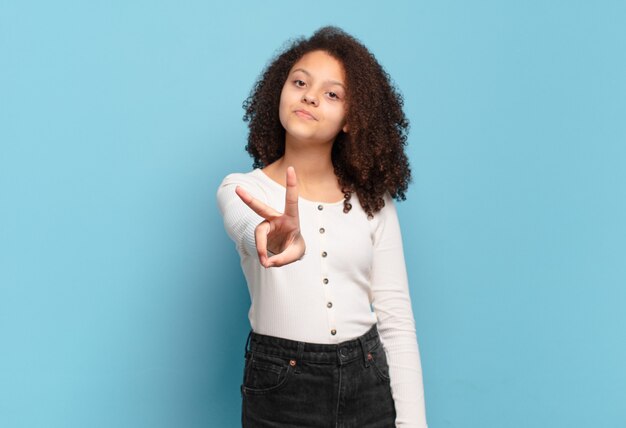 Jeune jolie femme faisant des gestes sur un mur de couleur