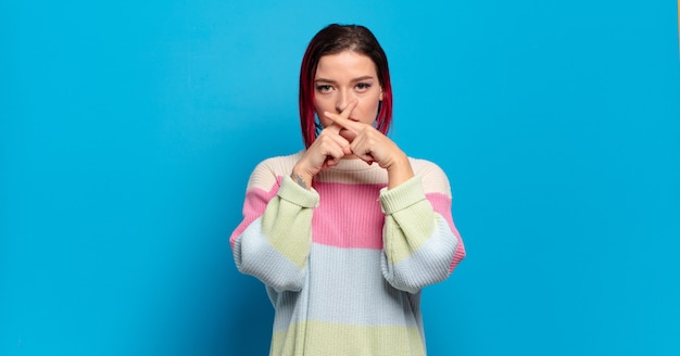 Jeune jolie femme faisant des gestes sur un mur de couleur