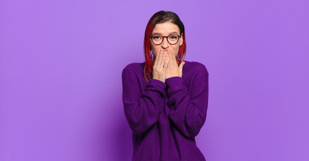 Jeune jolie femme faisant des gestes sur un mur de couleur