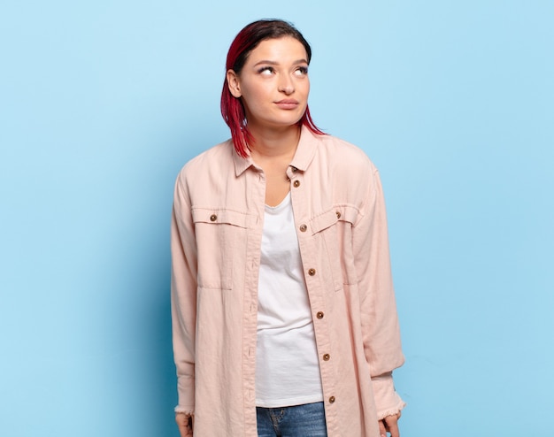 Jeune jolie femme faisant des gestes sur un mur de couleur