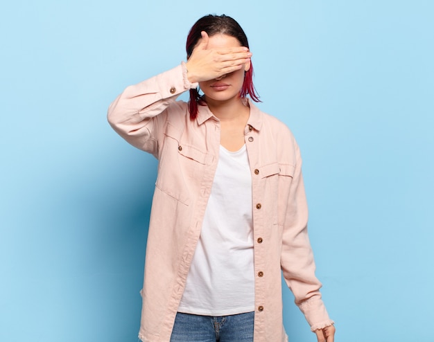 Jeune jolie femme faisant des gestes sur un mur de couleur