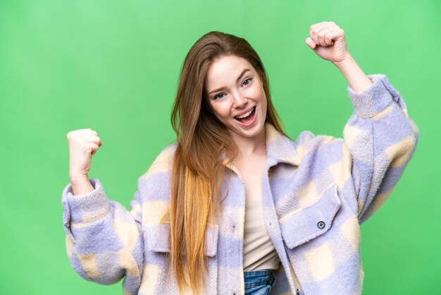 Jeune jolie femme sur fond isolé chroma key célébrant une victoire