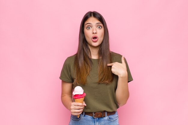 Jeune jolie femme avec une glace à choqué et surpris avec la bouche grande ouverte, pointant vers soi