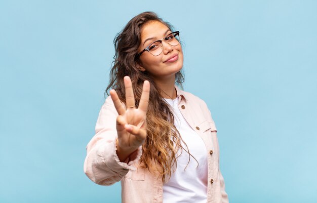 jeune jolie femme avec un grand sourire amical et insouciant, à la recherche positive, détendue et heureuse, effrayante. concept de maison