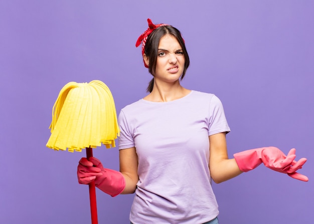 Jeune jolie femme haussant les épaules avec une expression stupide, folle, confuse, perplexe, se sentant agacée et désemparée