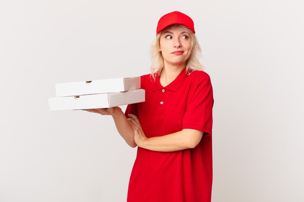 Jeune jolie femme haussant les épaules, se sentant confuse et incertaine. concept de livraison de pizza