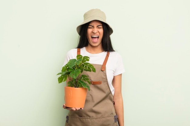 Jeune jolie femme hispanique criant agressivement à la recherche d'un concept d'agriculteur ou de jardinier très en colère