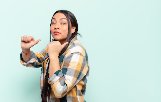 Jeune jolie femme hispanique avec un espace de copie contre un mur isolé