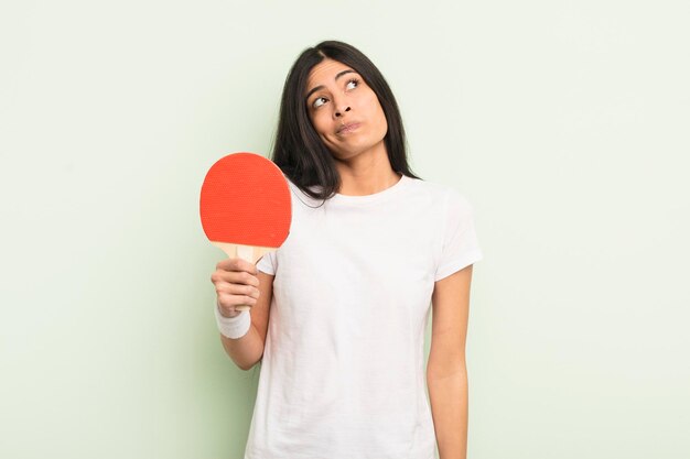 Jeune jolie femme hispanique haussant les épaules se sentant confus et incertain concept de ping-pong